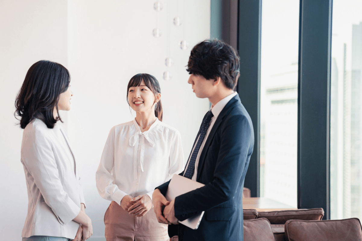 オフィスでスーツ姿のビジネスパーソンたちが笑顔で並んでいる