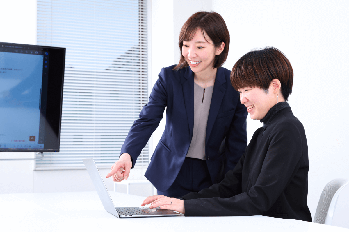 明るいオフィスで打ち合わせをするスーツ姿の男女4人